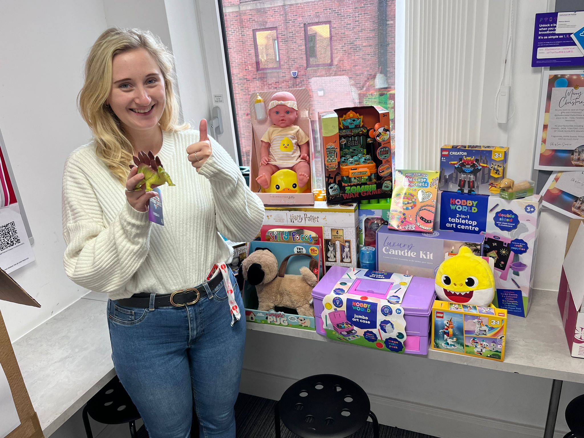 Person smiling next to toy donations